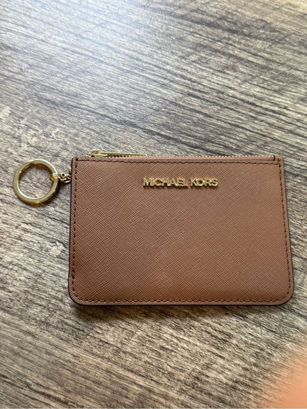 This is a brown Saffiano leather Michael Kors Jet Set Travel coin pouch.